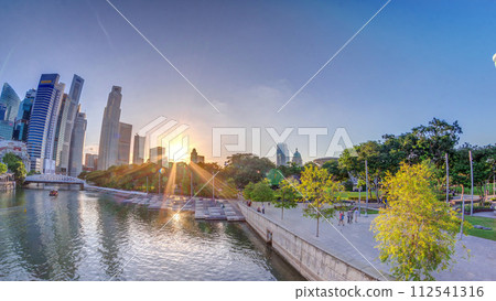 Sunset over Singapore skyscrapers skyline with white Anderson Bridge near esplanade park timelapse. 112541316