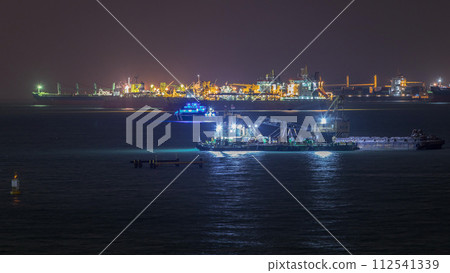 Singapore Marina Barrage with cargo ships waiting to enter one of the busiest ports in the world night timelapse, Singapore. 112541339