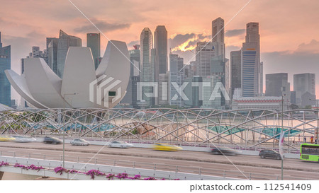 Aerial view of sunset over Helix Bridge and Bayfront Avenue with traffic timelapse at Marina Bay, Singapore 112541409