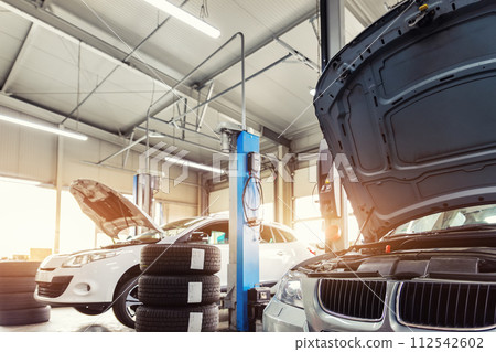 Car service center garage workshop. Vehicle raised on lift at maintenance station. Automobile repair and check up. Automotive insurance and technical checkup inspection diagnostic 112542602