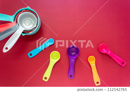 Collection of colorful measuring cups, measuring spoons use in cooking process on red background Collection of colorful measuring cups, measuring spoons use in cooking process on red background 112542765