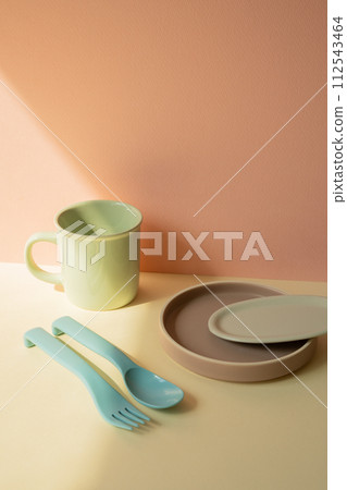 Kitchen cutlery fork and spoon, mug cup, dish plate on ivory shelf. pink wall background Kitchen cutlery fork and spoon, mug cup, dish plate on ivory shelf. pink wall background 112543464