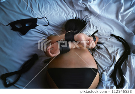 Sexy lingerie model in bdsm with a masked woman with a perfect figure wearing a belt on the bed Sexy lingerie model in bdsm with a masked woman with a perfect figure wearing a belt on the bed 112546528