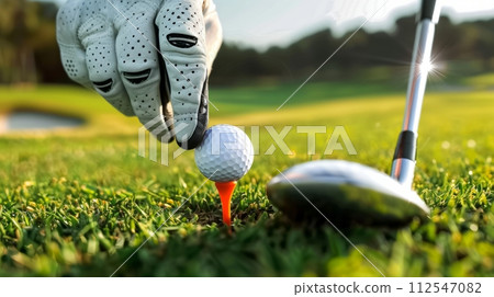 AI-generated content. Hand in glove putting golf ball on tee with club in golf course on evening and sunset time for healthy sport. AI-generated content. Hand in glove putting golf ball on tee with club in golf course on evening and sunset time for healthy sport. 112547082