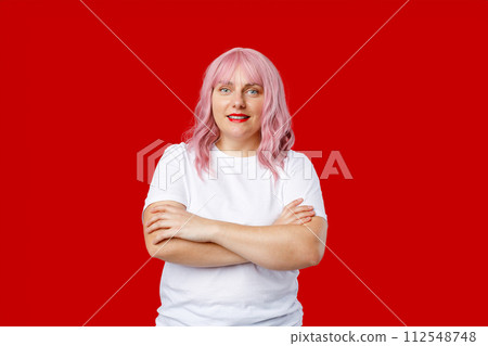 Excited happy 30s woman with pink hair standing on red background in studio. Crossed arms. 112548748