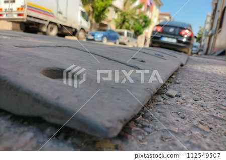 Plastic reclining policeman close-up against a blurred background of street conditions, cars, asphalt. The topic of safety of pedestrians and other road users in the yards Plastic reclining policeman close-up against a blurred background of street conditions, cars, asphalt. The topic of safety of pedestrians and other road users in the yards 112549507