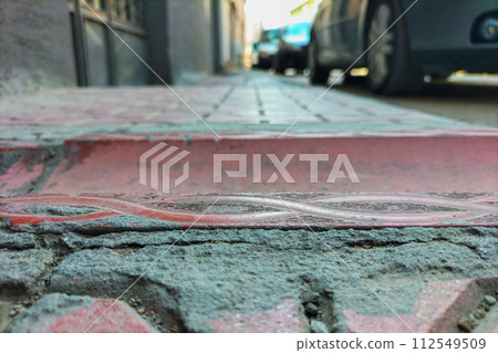 Decorated concrete gutter for rainwater drainage on sidewalk close-up with a street perspective. Concept of walk along street with a view of the details of the decoration of the elements of street Decorated concrete gutter for rainwater drainage on sidewalk close-up with a street perspective. Concept of walk along street with a view of the details of the decoration of the elements of street 112549509