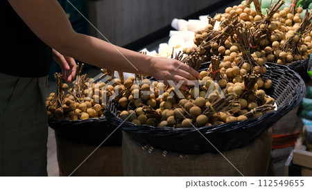Young woman buying fresh lychee at grocery store in Thailand. Healthy food concept Young woman buying fresh lychee at grocery store in Thailand. Healthy food concept 112549655