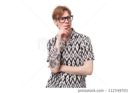 close-up of a young red-haired man in glasses with a tattoo on his arm looking to the side close-up of a young red-haired man in glasses with a tattoo on his arm looking to the side 112549703