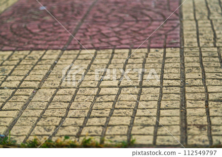 Textured surface of paving slabs running along lines, between which certain drawings are drawn. Theme of overcoming life path in which person observes various situations and gains experience 112549797
