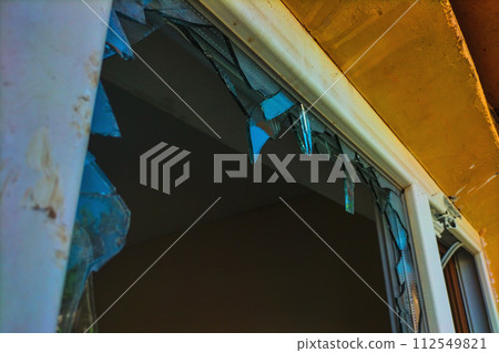 A broken plastic window with the remaining fragments through which thieves entered and stole valuables. The concept of security, private property, looting, theft, robbers, refugees, riots, attacks 112549821