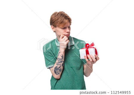 a young european man with red hair thinks what was given to him in a box with a ribbon a young european man with red hair thinks what was given to him in a box with a ribbon 112549955