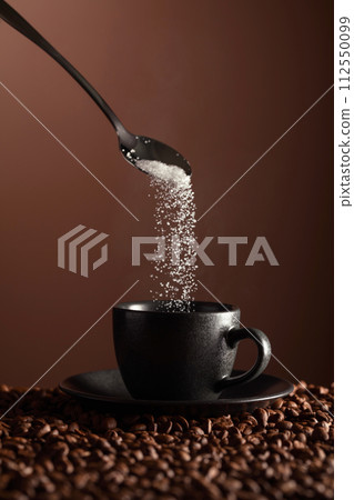 Sugar is poured into a cup of coffee. Sugar is poured into a cup of coffee. 112550099