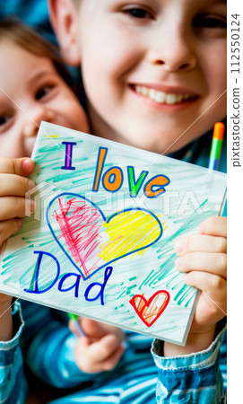 Two cute smiling little girls Daughters holding in their hands a drawing of a congratulation with colored pencils with the inscription I love dad and hearts for Father's Day 112550124
