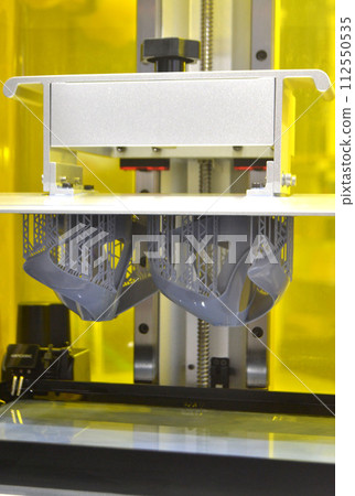Printed models on 3D printer close-up. Objects printed on photopolymer sla 3D printer from liquid photopolymer resins on printing platform inside 3d printer. Modern progressive additive technology. 112550535