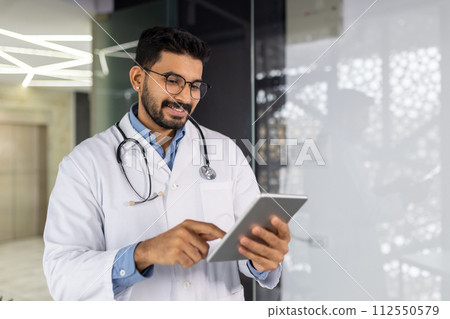 Confident young male healthcare professional working with a tablet in a bright medical office setting, embodying the blend of technology and care. Confident young male healthcare professional working with a tablet in a bright medical office setting, embodying the blend of technology and care. 112550579