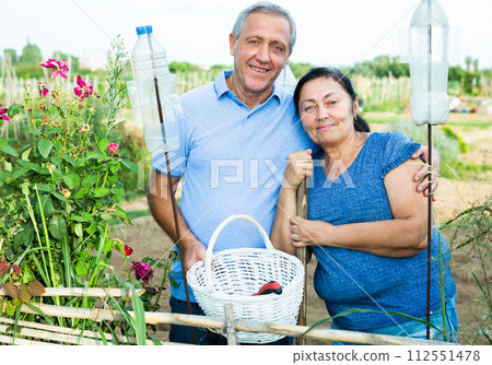 Male and female gardeners with gardening tools posing in summer garden 112551478