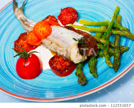 Baked fish poutassou with dried tomatoes, asparagus and creamy-garlic sauce 112551657