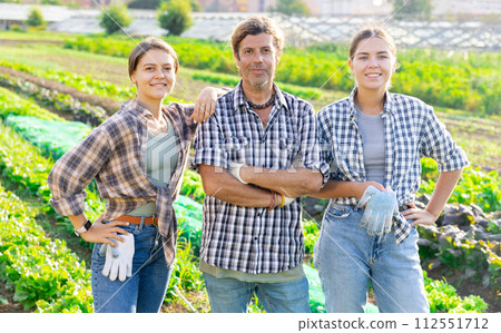 Portrait of three happy farmers against the backdrop of a field with vegetable harvest 112551712