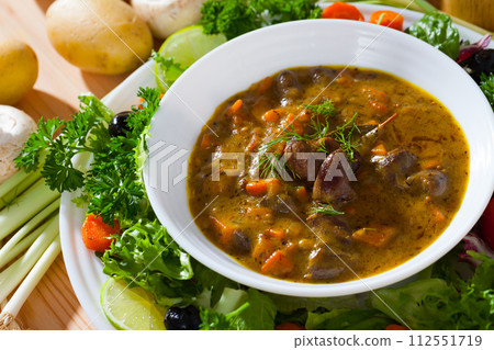 Cooked goulash from chicken hearts with vegetables and fresh lettuce Cooked goulash from chicken hearts with vegetables and fresh lettuce 112551719