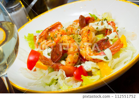 Salad with grilled shrimps, chorizo, vegetables and lemon 112551752