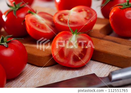 Cut fresh tomatoes on wooden table in home kitchen 112551765