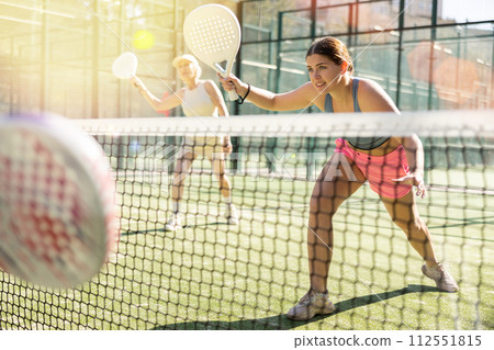 Young woman playing Padel Tennis in open-air tennis court Young woman playing Padel Tennis in open-air tennis court 112551815