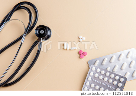 The black and steel phonendoscope, stethoscope, pills on a yellow background. 112551818