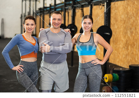 Positive man and young women in activewear posing during workout in gym fitness center 112551821