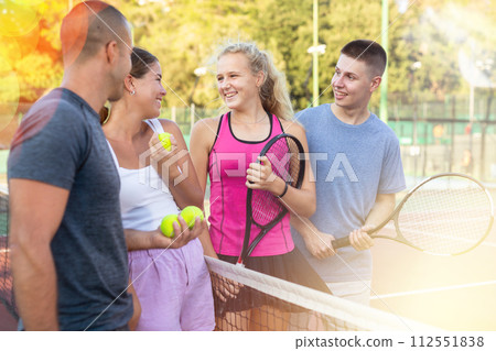Men and women having conversation on outdoor tennis court 112551838