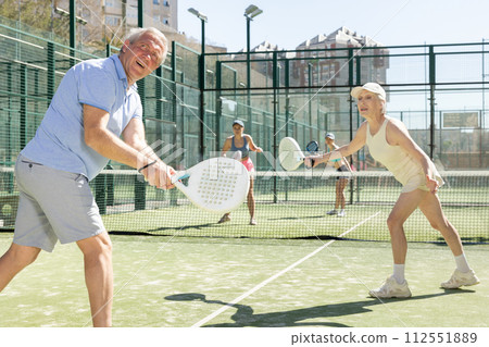 Determined sporty older husband and wife doing his best playing padel in court Determined sporty older husband and wife doing his best playing padel in court 112551889