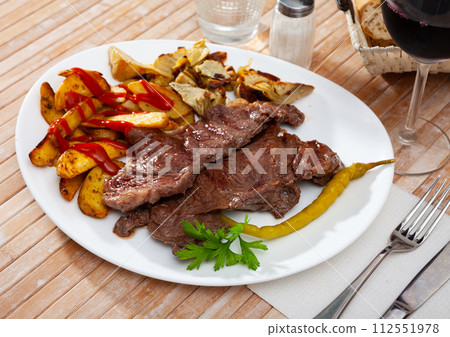 Veal steak with grilled potato and artichokes 112551978