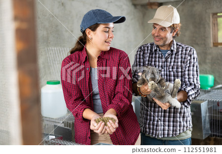 Married couple feeds and cares for rabbits on farm 112551981