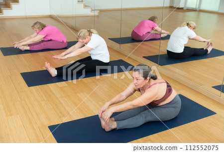 Group of active senior women practicing yoga Group of active senior women practicing yoga 112552075