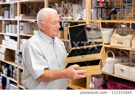 Elderly man looking for storage box for accessories Elderly man looking for storage box for accessories 112552084