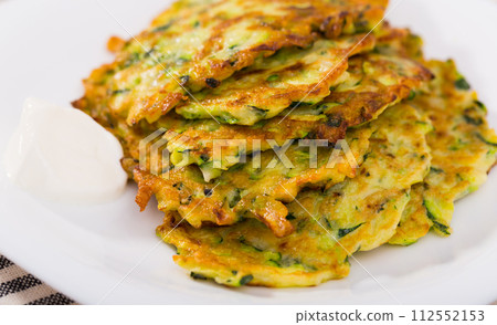 Zucchini pancakes with sour cream 112552153