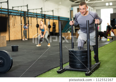 Man during grueling workout with element of push and pull superset in fitness club 112552167