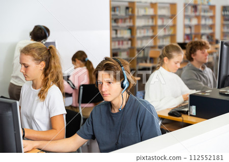 Portrait of a fifteen-year-old schoolboy in headphones at a computer 112552181