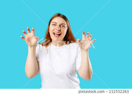 Pretty cheerful woman smiling funny and doing claw gesture as cat, aggressive and sexy expression. Studio portrait. 112552263