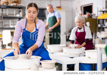 Young woman learning how to create pottery on potter wheel in workshop 112552516