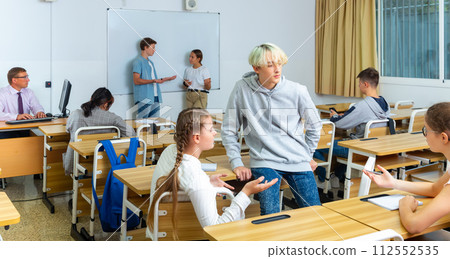 Positive students are talking about homework at desk Positive students are talking about homework at desk 112552535