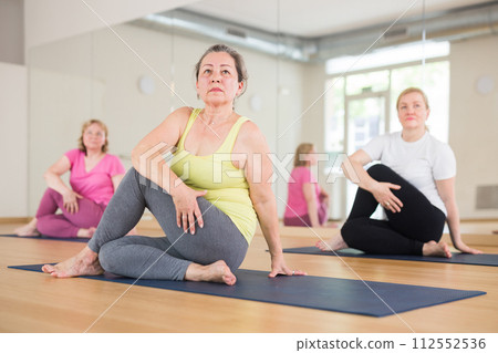 Aged women are doing lord of the fishes pose 112552536