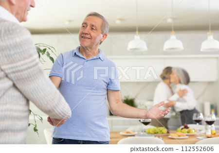 In home, mature male friends shake hands, say goodbye after socializing and gatherings. In home, mature male friends shake hands, say goodbye after socializing and gatherings. 112552606