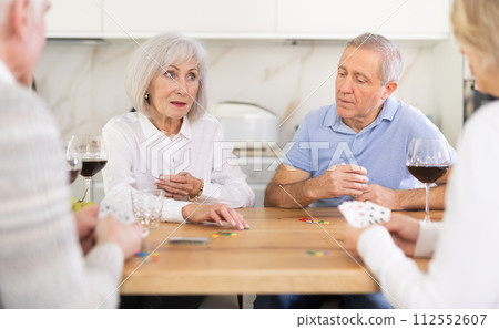 Two mature married couples playing card game poker Two mature married couples playing card game poker 112552607