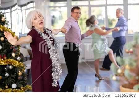 Middle-aged man and elderly woman dancing contemporary discofox in couple in New Year atmosphere Middle-aged man and elderly woman dancing contemporary discofox in couple in New Year atmosphere 112552608