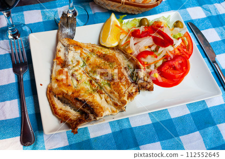 Grilled dorada with pesto, lemon slice and salad of fresh vegetables Grilled dorada with pesto, lemon slice and salad of fresh vegetables 112552645