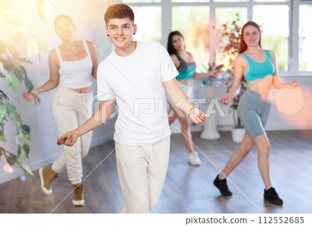 Positive male teenager learns to dance groove, perform movements in choreographic class with peers 112552685
