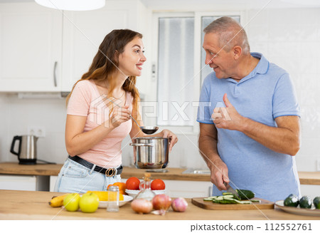 Happy father spending time with adult daughter - preparing lunch together in kitchen Happy father spending time with adult daughter - preparing lunch together in kitchen 112552761