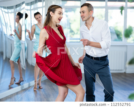 Smiling woman in red dancing twist with man in dance studio 112552791