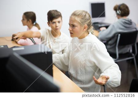 Schoolchildren preparing for lessons on the computer Schoolchildren preparing for lessons on the computer 112552816